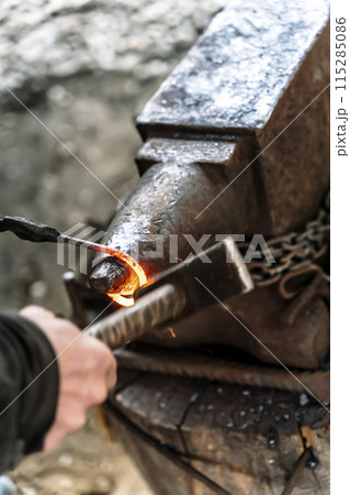 Blacksmith in a forge at work on an anvil. Hot metal forging 115285086