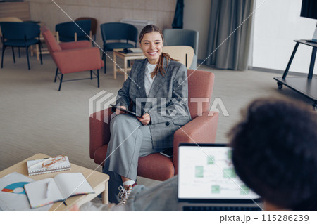 Smiling female coworkers talking during business meeting in cozy office. Teamwork concept 115286239