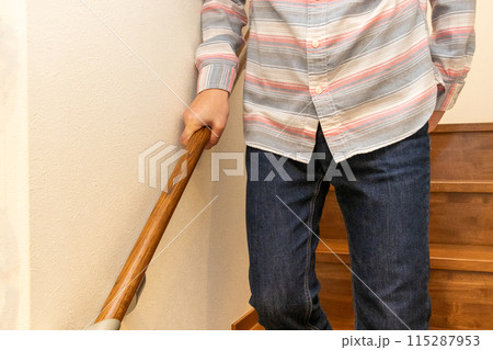 手すりを握って階段を下りる男性 115287953