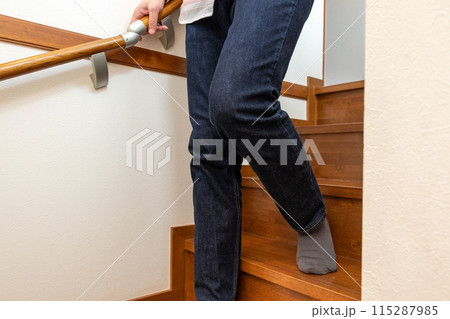 手すりを握って階段を下りる人物 115287985
