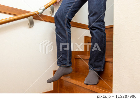 手すりを握って階段を下りる人物 115287986