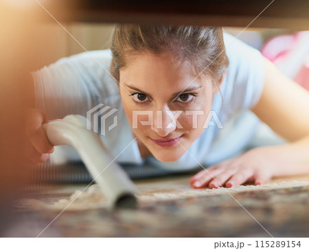 Woman, vacuum and cleaning carpet floor in home for hygiene, housework or housekeeping service in living room. Chores, maid and electrical machine to remove dirt, dust and bacteria with face closeup 115289154
