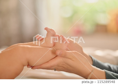 Baby, feet and hands massage in bedroom for care, love and bonding with adorable cute kid in family home nursery together. Foot, infant and child closeup on bed for development, health or parenting 115289548