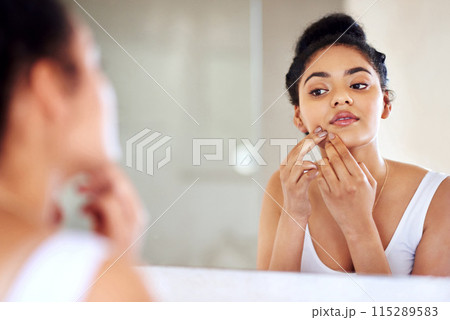 Skincare, woman and mirror to pop pimple on face with hands, dirt or scar on skin in home. Dermatology, facial wellness and girl in bathroom to squeeze acne, checking reflection or morning routine 115289583