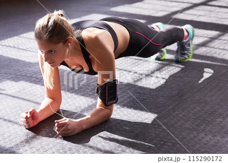 Fitness, plank and woman with music in gym for workout, training and strength for core muscle. Female athlete, physical activity or exercise with balance, endurance or commitment or headset in sports 115290172