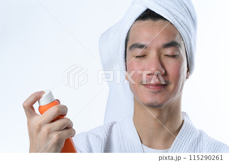 Young man spraying sunscreen on his face. UV protection and aesthetic face treatment concept 115290261