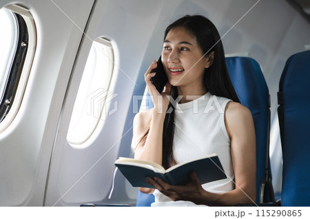 Waist up image of a fun business woman in an airline working on his computer while talking on a cell phone. 115290865