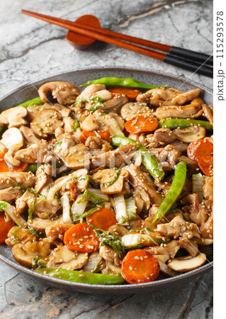 Moo goo gai pan Chinese American version is a simple stir-fried dish with thin sliced chicken, mushrooms and other vegetables closeup on the plate. Vertical 115293578