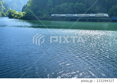 逆光で輝く下原ダム湖沿いを走るHC85系特急「ひだ」 115294327