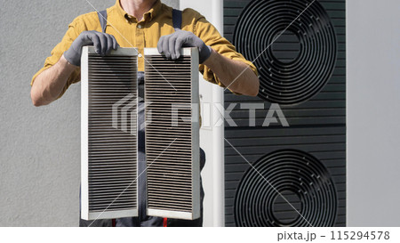 Plumber holding two heavily clogged air filters from a home air conditioning system. Plumber holding two heavily clogged air filters from a home air conditioning system. 115294578
