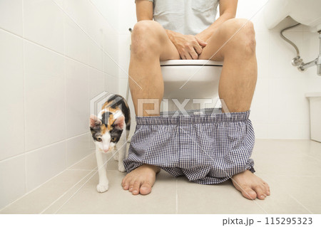 Close up view of man sitting on toilet bowl in rest room Close up view of man sitting on toilet bowl in rest room 115295323