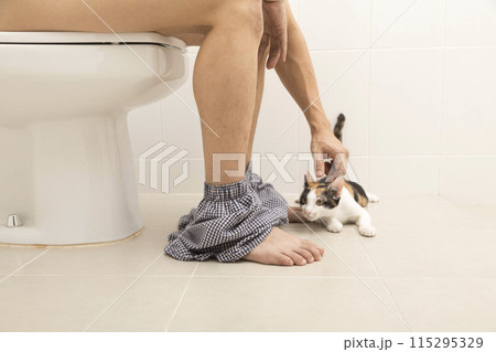 Close up view of man sitting on toilet bowl in rest room Close up view of man sitting on toilet bowl in rest room 115295329