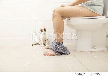 Close up view of man sitting on toilet bowl in rest room 115295330