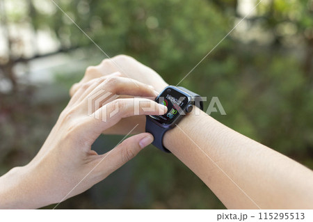 Woman uses the smartwatch to check the latest notifications and messages outside 115295513