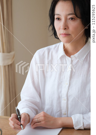 リビングで家族への手紙を書くミドル女性 115295625