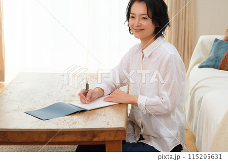 リビングで家族への手紙を書くミドル女性 115295631