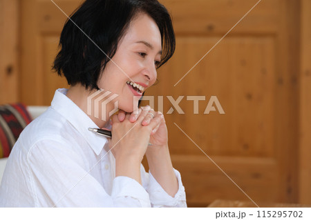 リビングで家族への手紙を書くミドル女性 115295702