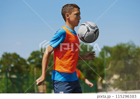Focused and concentrated boy in colorful sportswear in motion, practicing soccer game outdoor, hitting ball with chest. Focused and concentrated boy in colorful sportswear in motion, practicing soccer game outdoor, hitting ball with chest. 115296383