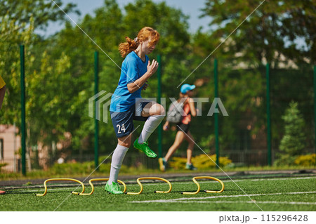 Intensive Sports Practice. Dedicated young female athlete in blue uniform training on agility ladder, working on footwork and quick reactions. 115296428