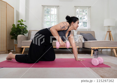 Determined Overweight Woman Exercising at Home with Dumbbells, Committed to Weight Loss and Fitness Journey, Demonstrating Strength and Dedication in a Modern Living Room Setting 115297162