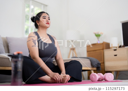 Confident Woman Practicing Yoga at Home, Embracing Healthy Lifestyle and Weight Loss Journey, Sitting on Yoga Mat with Dumbbells in Modern Bedroom, Promoting Fitness and Self Care Confident Woman Practicing Yoga at Home, Embracing Healthy Lifestyle and Weight Loss Journey, Sitting on Yoga Mat with Dumbbells in Modern Bedroom, Promoting Fitness and Self Care 115297173