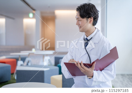 病院で笑顔でカルテに記入する男性医師 115297185