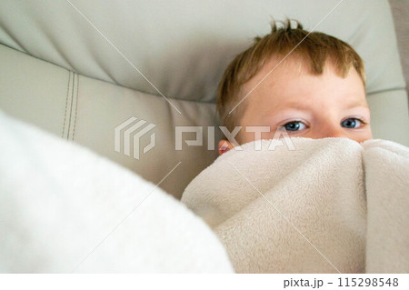 Cold season, a frozen preschool boy covered with warm plaid spend time at home, , winter family lifestyle. Power crisis concept, problem with heating. High quality photo Cold season, a frozen preschool boy covered with warm plaid spend time at home, , winter family lifestyle. Power crisis concept, problem with heating. High quality photo 115298548