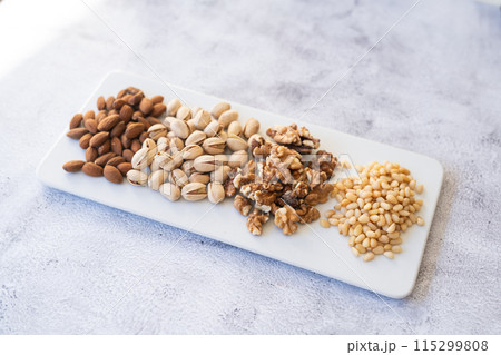 Mix of different nuts on a white plate. 115299808