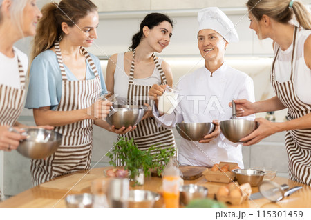 Elderly woman chef with bowl in hands tells women at culinary courses about traditions of cuisine Elderly woman chef with bowl in hands tells women at culinary courses about traditions of cuisine 115301459