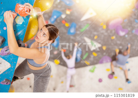 Young woman practicing rock climbing on climbing wall Young woman practicing rock climbing on climbing wall 115301819