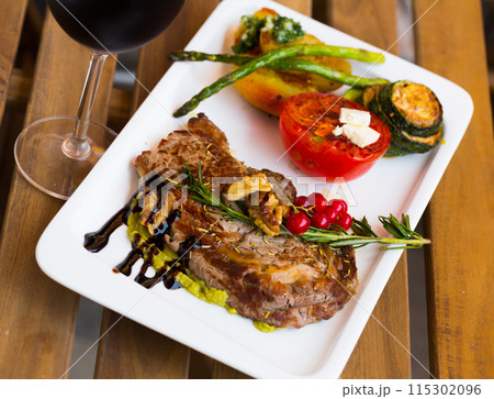Fried beef loin with avocado puree and vegetables on wooden background 115302096