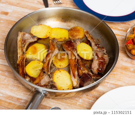 Seared and roasted lamb ribs served with baked potato on table, top view. 115302151