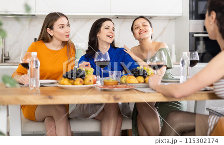 Girlfriends chatting and drinking wine in kitchen Girlfriends chatting and drinking wine in kitchen 115302174