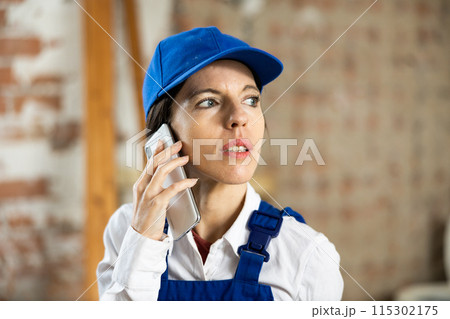 Female contractor talking on phone at construction site indoors 115302175