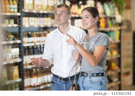 Young couple looking for fresh produce in natural foods store Young couple looking for fresh produce in natural foods store 115302191