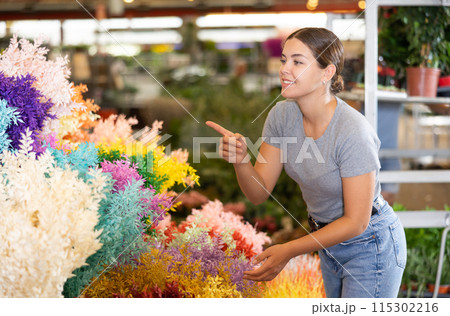 Girl choosing branches of colorful Italian ruscus at flower market Girl choosing branches of colorful Italian ruscus at flower market 115302216