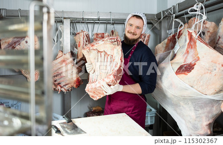 Male butcher shop butcher shows raw chopped carcasses and ribs Male butcher shop butcher shows raw chopped carcasses and ribs 115302367