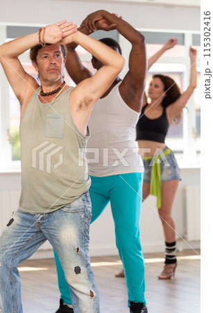 Man in ripped jeans practicing expressive vogue dance at group class 115302416