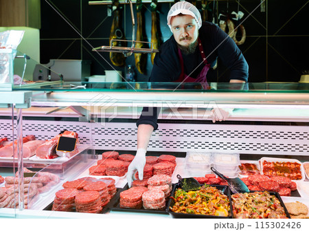 Man butcher holding meat cutlets in meat section of supermarket 115302426