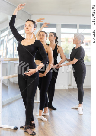 Elderly woman teacher corrects female dancers 115302503