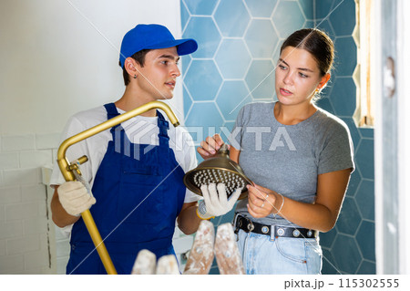 Woman asking for help from plumber in assembling new shower during renovation 115302555