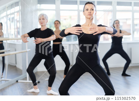 Woman practicing basic movements during group ballet class Woman practicing basic movements during group ballet class 115302570