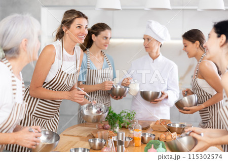 Young woman holding bowl and talking to other members Young woman holding bowl and talking to other members 115302574