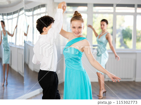Couple of teenage dancers rehearsing ballroom dance with female teacher 115302773