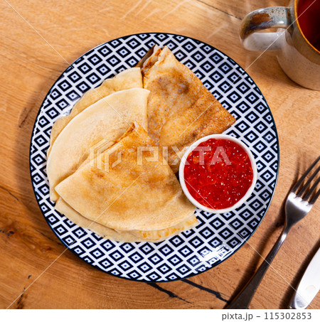 Service plate containing fried hotcakes with red caviar. Popular Russian dish 115302853