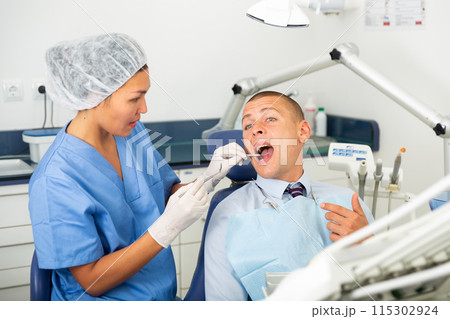 Dentist inspects male patient teeth Dentist inspects male patient teeth 115302924