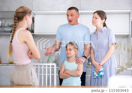 Girl with hair in braids stands in front of parents and listens to instructions about bad behavior Girl with hair in braids stands in front of parents and listens to instructions about bad behavior 115303043