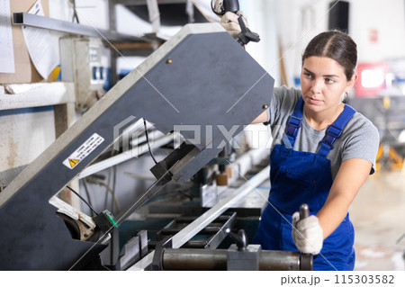 Workwoman cutting PVC profile on industrial machine in workshop 115303582