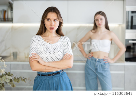 Two young women quarrel in kitchen at home Two young women quarrel in kitchen at home 115303645