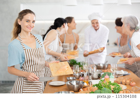 Young woman holding cutting board with raw chicken breast Young woman holding cutting board with raw chicken breast 115304108